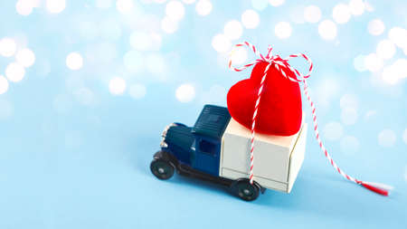 Little car carries a red heart. Concept of Valentine Day. Valentine's Day card. Copy space