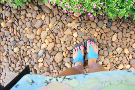 flip flops on their feet on the background of pebblesの写真素材