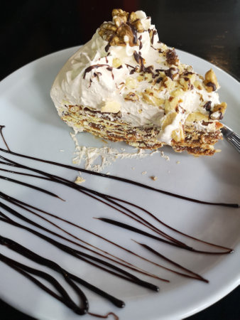 Coffee cake with whipped cream and chocolate on a white plateの写真素材