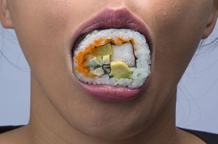 woman eating sushi having sushi in her mouthの写真素材