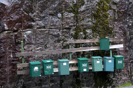 green mailboxes on stonewall near house