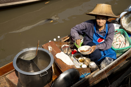 woman cooking en selling noodle soup from her boat  at floating market Bangkokのeditorial素材