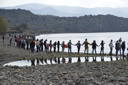 LESVOS, GREECE February 27, 2016: Greek man and woman, children, volunteers and refugees are...