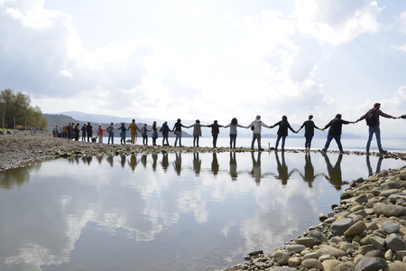 LESVOS, GREECE February 27, 2016: Greek man and woman, children, volunteers and refugees are standing hand in hand to make a message to the world, 'SafePassage'のeditorial素材