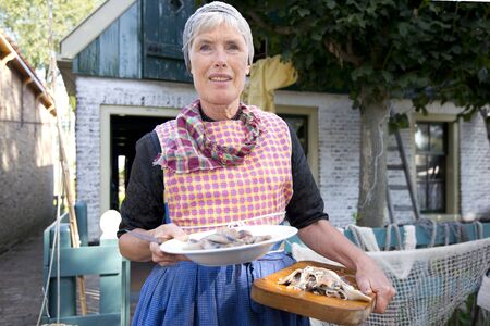 The Netherlands, Enkhuizen,10-09-2016: Woman with raw herring an traditional mealのeditorial素材