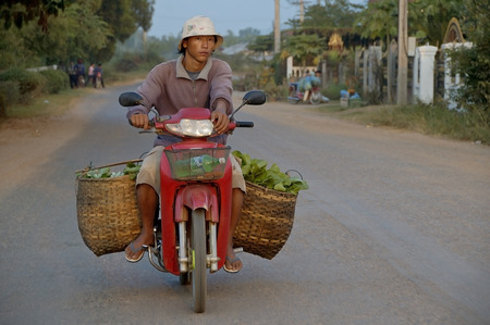 Luang Prabang, Laos, 29 oct, 2007. Man riding his scooter with basket full of vegetables on the street of Luang Prabangのeditorial素材
