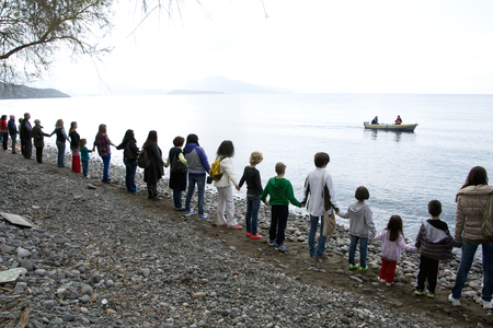 LESVOS, GREECE February 27, 2016: Greek man and woman, children, volunteers and refugees are standing hand in hand to make a message to the world, 'SafePassage'のeditorial素材