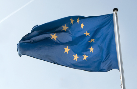 The flag of the European Union as it waves in the wind. Its dark blue colour is in beautiful contrast to the light blue sky.の写真素材