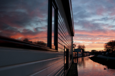 Houseboats in a beautiful pink sunset. The sky reflecting in the water and the windows.の写真素材