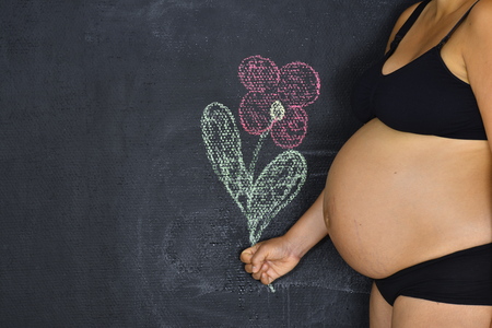 A pregnant woman holding a flower drawn on the chalkboard.の写真素材