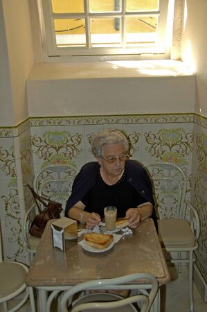 Lisbao, Portugal, 27-September-2007: An old woman enjoying her breakfast by herself in Lisbao.のeditorial素材