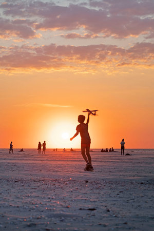 Ameland-The Netherlands-13-08-2022: Boy flying a plane at the beach.のeditorial素材