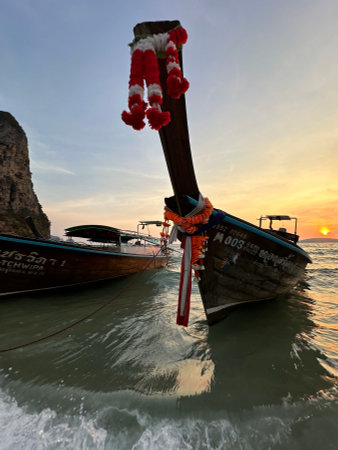 A couple of boats can be seen floating in the water at sunsetの写真素材