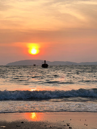 As the sun sets beautifully over the vast ocean, a distant boat floatsの写真素材