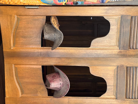 Two stylish cowboy hats are gracefully positioned within a wooden cabinetの写真素材