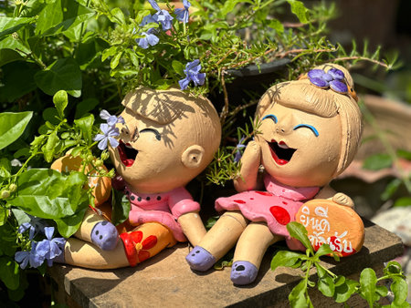 Two delightful clay dolls are sitting side by side on a wooden blockの写真素材