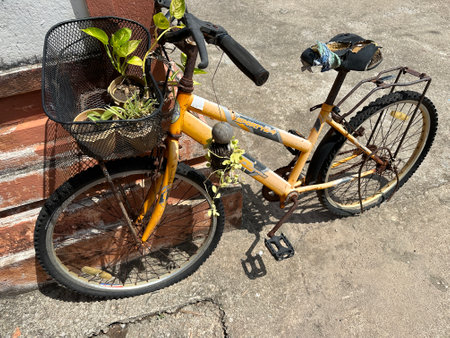 A bike with a basket is parked on the sidewalk by a brick wallの写真素材
