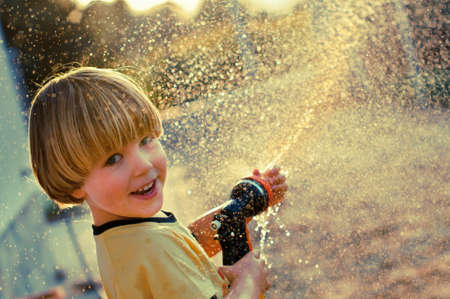 A young boy playing with a garden sprinklerの写真素材