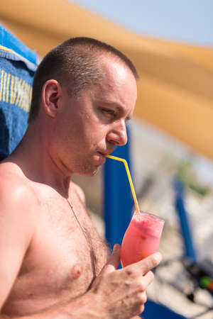 Handsom man sipping a drink at a hotel swimming poolの写真素材