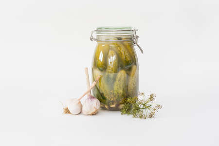 A jar of homemade salt cucumbers with garlic and dill next to the jarの写真素材