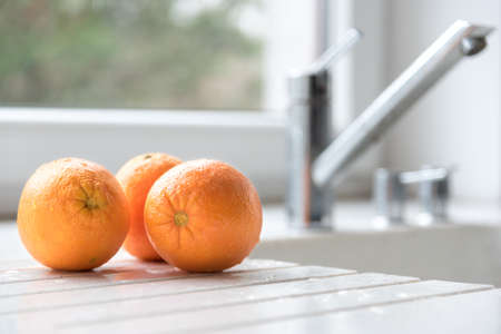 Freshed washed juicy oranges on a white stone kitchen worktopの写真素材