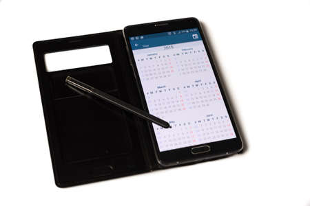 Stylus lying on a smartphone with a calendar application openedの写真素材