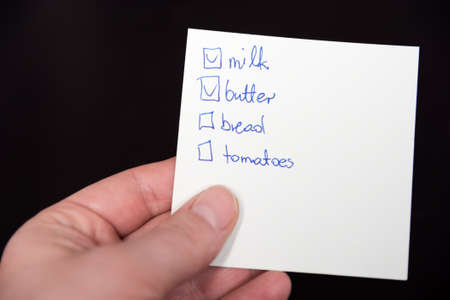 Isolated hand holding a shoping list on a black backgroundの写真素材