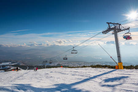 Ski lift, small village and clouds in background and clouds in background, Strbskie Pleso, Slovakiaの写真素材