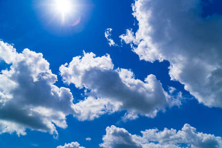 Deep blue sky filled with big puffy clouds lit by summer sunの写真素材