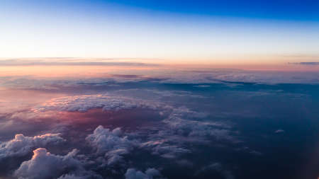 Birds-eye view down to clouds lit with a worm light of setting sun.
