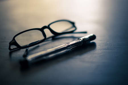 Glasses and pen on a tableの写真素材