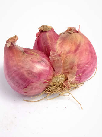 Small onion purple in color.Three onions together and can see the roots with it.Loosen dry skin is also visible in the image.Image is clear and focused on the subject.の写真素材