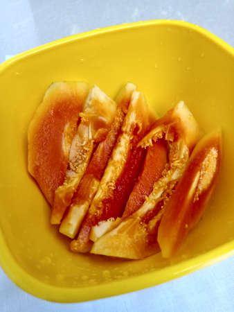 Papaya slices placed inside a yellow dish.Can see the section inside the papaya.Section has a red to yellow gradient color.の写真素材