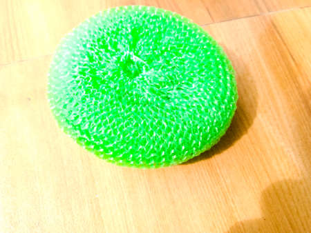 A top angle view of a plastic green color dish scrubber lying on the floor under sunlight.The scrubber is plastic in material.の写真素材