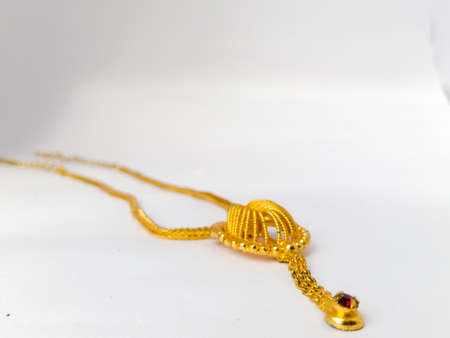 A Top view of a golden necklace placed isolated in a white background.The necklace has a 3d design...