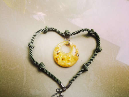 A nice necklace with stone pendant and a rope link.The stone pendant has yellow color and the rope has green color.The ends of the link is joining each other.の写真素材