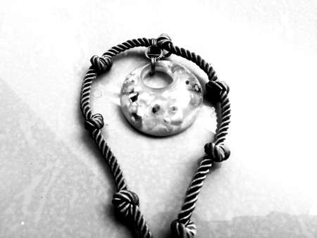 A top view of a necklace placed isolated on a floor with a rope link and stone pendant.The necklace...