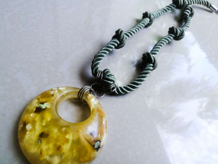 A long necklace with its link as knotted and have a stone pendant in it.The stone has yellow color and the rope has a green color.の写真素材