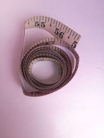 A tailoring meter tape placed isolated in a white background.The markings on the tape is visible and the outer side has pink and the inner side has white color.の写真素材