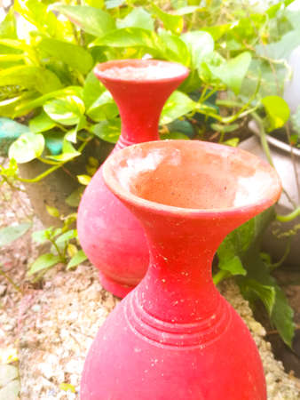 A top angle view of two earthen pots placed in a garden.The pots have big mouth and a narrow neck.The background have greens.の写真素材