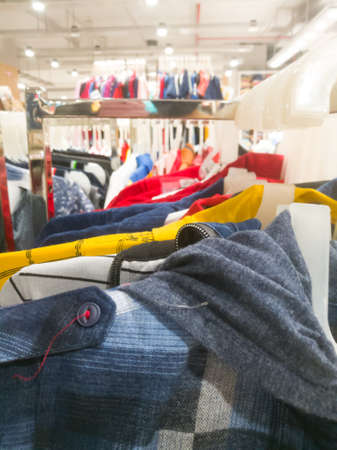 Left side view of an array of shirts hanging in hangers in a textile showroom.The hangers are hanging on a single bar.の写真素材