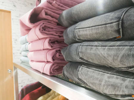 A side angle view of a stack of pants placed on the shelves.The pants have ash colored and pink colored pants.の写真素材
