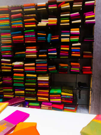 A Huge collections of different colored sarees and materials placed in a shelf.The materials are well stacked and arranged.A view from a textile showroom.の写真素材