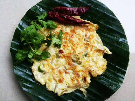 Egg Omelette with coriander leaves and Red chillies in a banana leaf.The banana leaf has green color...