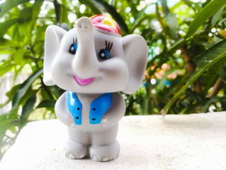 Toy elephant wearing a blue coat and a cap on head.The elephant has grey color body and blue color coat and a cap of red and yellow color.Its eyes are blue colored.の写真素材