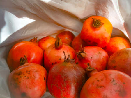 Pomegranate fruit from top angle showing its ends.The fruit skin is red colored and the ends are open.The adjacent pomegranate are visible.The skins are smooth and shiny in nature.の写真素材