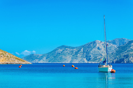 Sport yacht on anchor in silent bay on Greek Island, Greece