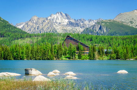 Amazing mountiain lake with wooden hotel at the bank and high peaks in background, Strbske Pleso, High Tatras in Slovakiaの写真素材