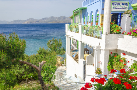 KALYMNOS, GREECE - MAY 01, 2015: Panoramic view on typical Greek restaurant with flowers and white teracce having clear view on sea landspace with islands, Greeceのeditorial素材