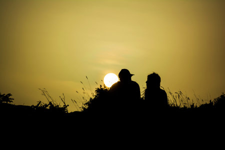 Couple silhouette watching the sun at sunset at Sounionの写真素材